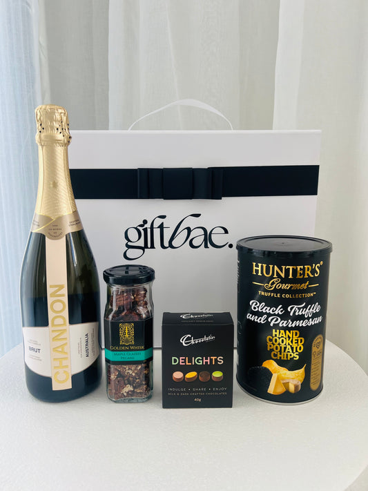 Gift basket with Chandon champagne, Hunter's black truffle potato chips, and other items on a white surface. | Luxury gift hampers Australia – beautifully curated gourmet hampers, wine gift boxes, and pamper hampers for all budgets. Perfect for birthdays, anniversaries, corporate gifts & special occasions. Gift Bae offers Perth same-day delivery & Australia-wide shipping. Shop the best gift hampers online today!